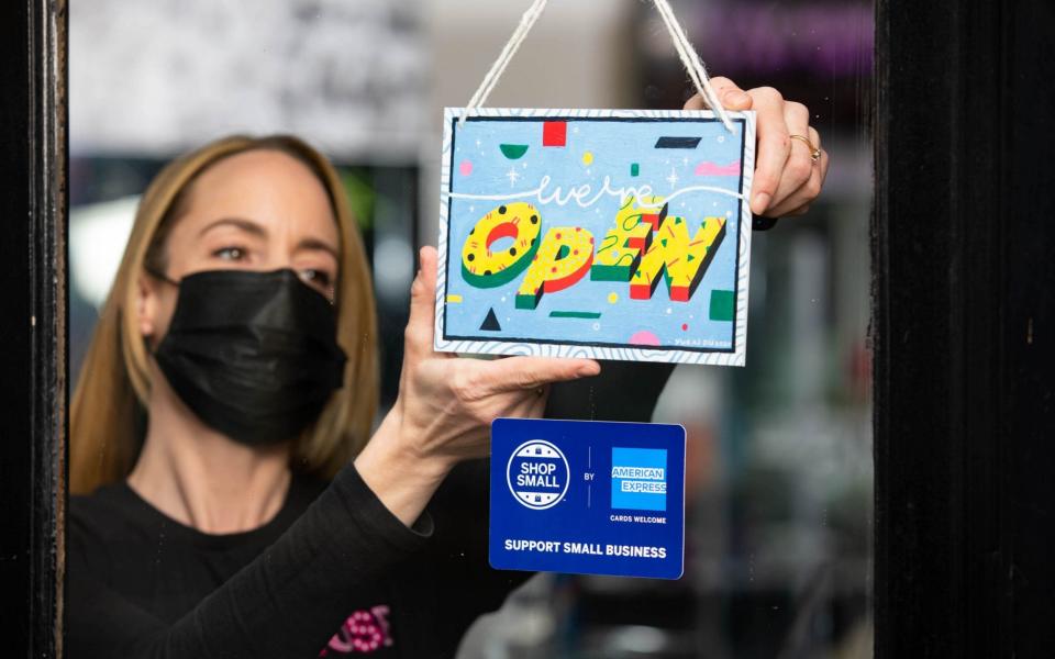  Manager Louise Hughes from Muse of London displays a "we're open" sign designed by artist Yukai Du, which has been created as part of the American Express Shop Small campaign and to help welcome people back to our high streets - David Parry 