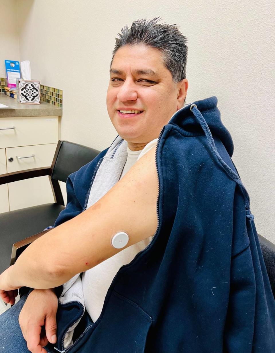 A Grace Clinic patient with diabetes shows his continuous glucose monitor, which he scans to get a real-time readout of his glucose levels.