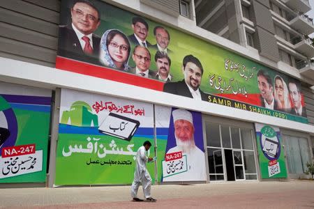 A man walks past an apartment building with campaign posters ahead of general elections in Karachi, Pakistan June 27, 2018. Picture taken June 27, 2018. REUTERS/Akhtar Soomro