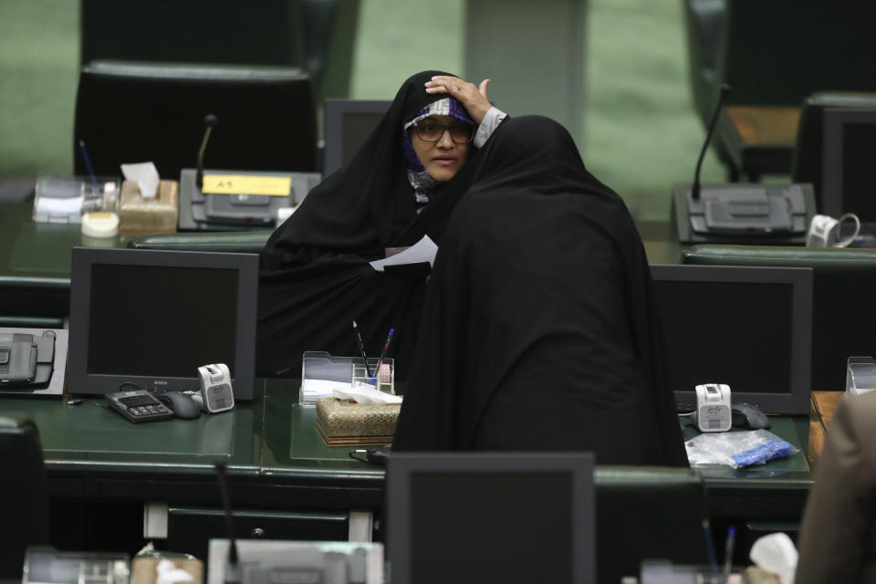 A lawmaker adjusts her veil as she talks with a colleague during the inauguration of Iran's new parliament, in Tehran, Iran, Wednesday, May, 27, 2020. Iran has convened its newly elected parliament, dominated by conservative lawmakers and under strict social distancing regulations, as the country struggles to curb the spread of coronavirus that has hit the nation hard. Iran is grappling with one of the deadliest outbreaks in the Middle East. (AP Photo/Vahid Salemi)