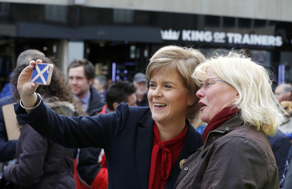 Nicola Sturgeon (L), leader of the Scottish National Party, takes a selfie photograph with a supporter during an election visit to Kirkcaldy in Scotland, Britain May 4, 2015. Britain will go to the polls in a national election on May 7. REUTERS/Russell Cheyne