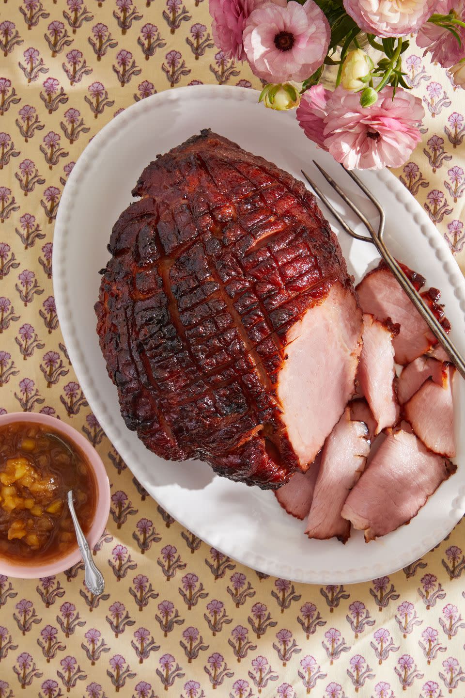 a glazed ham on a plate with some slices cut off