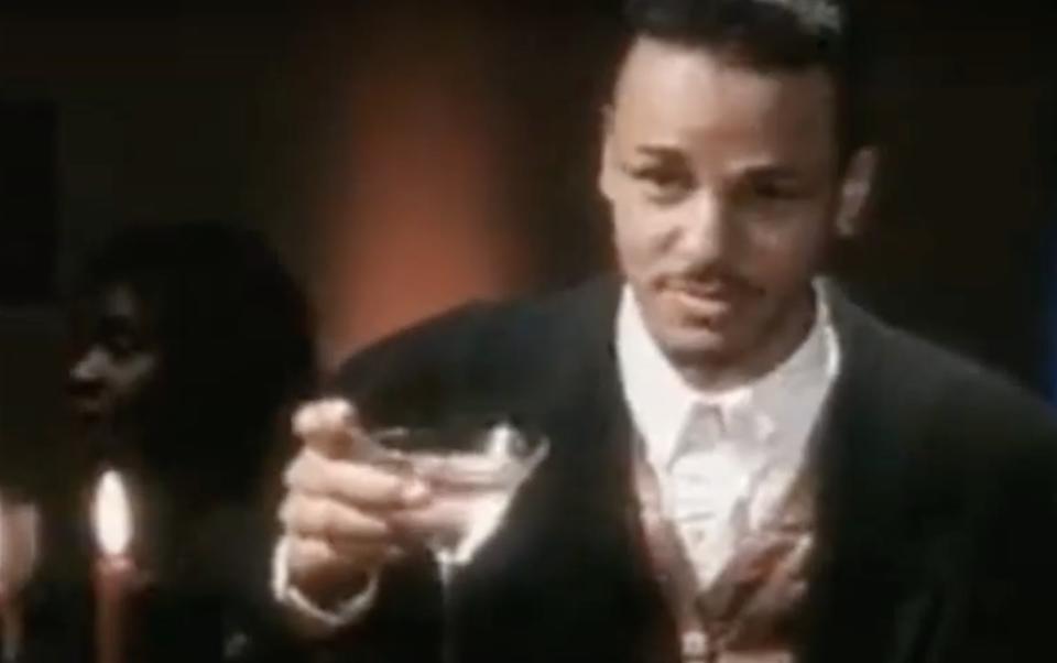 Actor Christopher Scott Cherot wears a suit and raises the martini glass in his hand.