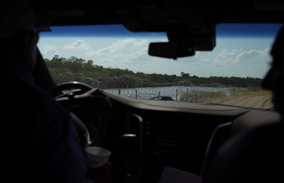 Hugo and Magali Urbina, drive on their pecan farm where the state has installed concertina wire along the banks, near Eagle Pass, Texas, Monday, July 7, 2023. Texas Republican Gov. Greg Abbott has escalated measures to keep migrants from entering the U.S. He's pushing legal boundaries along the border with Mexico to install razor wire, deploy massive buoys on the Rio Grande and bulldozing border islands in the river. (AP Photo/Eric Gay)