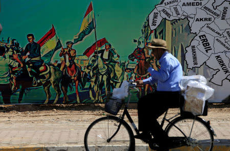 A man rides a bike near a mural supporting the referendum for independence of Kurdistan in Erbil, Iraq September 24, 2017. REUTERS/Alaa Al-Marjani