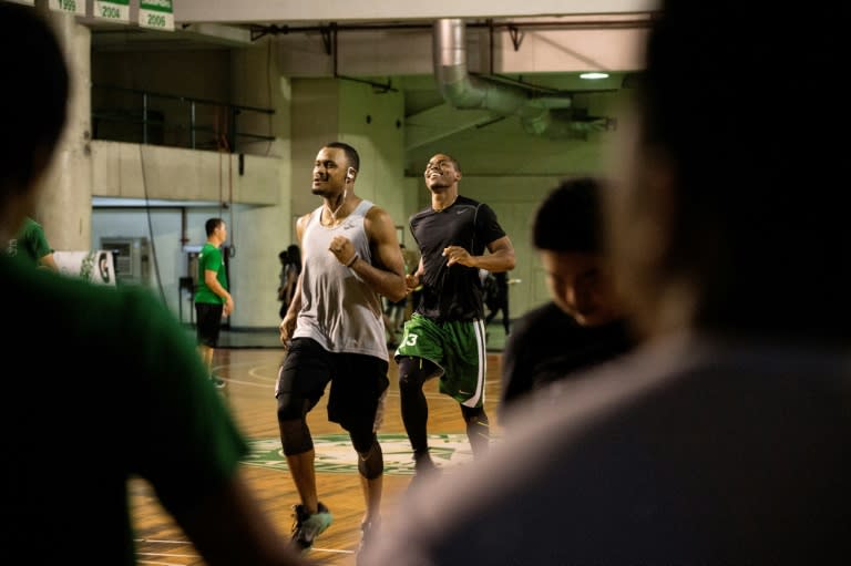 Cameroon's Benoit Mbala (centre, dark shirt) warms up with fellow college team members at De La Salle University's gym in Manila on January 24, 2017