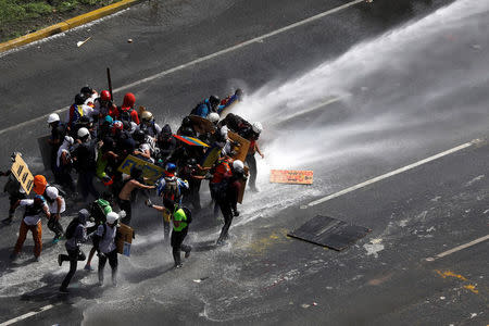 Demonstrators are hit by a jet of water during clashes at a march to the state Ombudsman's office in Caracas, Venezuela May 29, 2017. REUTERS/Carlos Garcia Rawlins