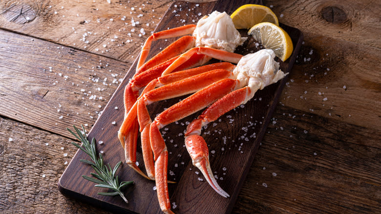 crab legs on cutting board with salt and lemon wedges