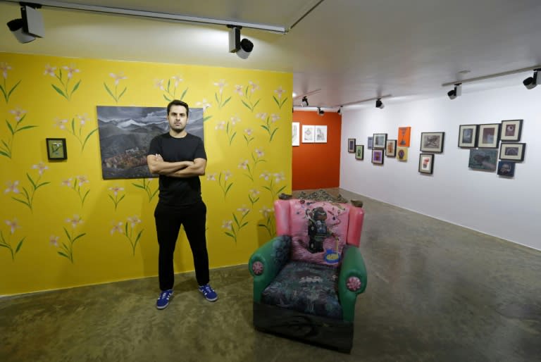Hormuz Hematian, founder of Dastan Gallery in Tehran, poses for a photo next to art-work during an interview with AFP at his gallery