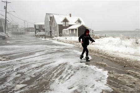 A woman runs from the surf as waves crash into houses on Lighthouse Road during a winter nor'easter snow storm in Scituate, Massachusetts January 3, 2014. REUTERS/Dominick Reuter
