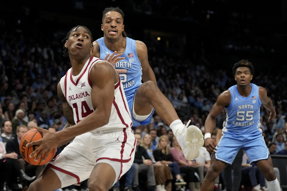 Oklahoma forward Jalon Moore drives to the basket past North Carolina forward Armando Bacot during the first half of an NCAA college basketball game Wednesday, Dec. 20, 2023, in Charlotte, N.C. (AP Photo/Chris Carlson)