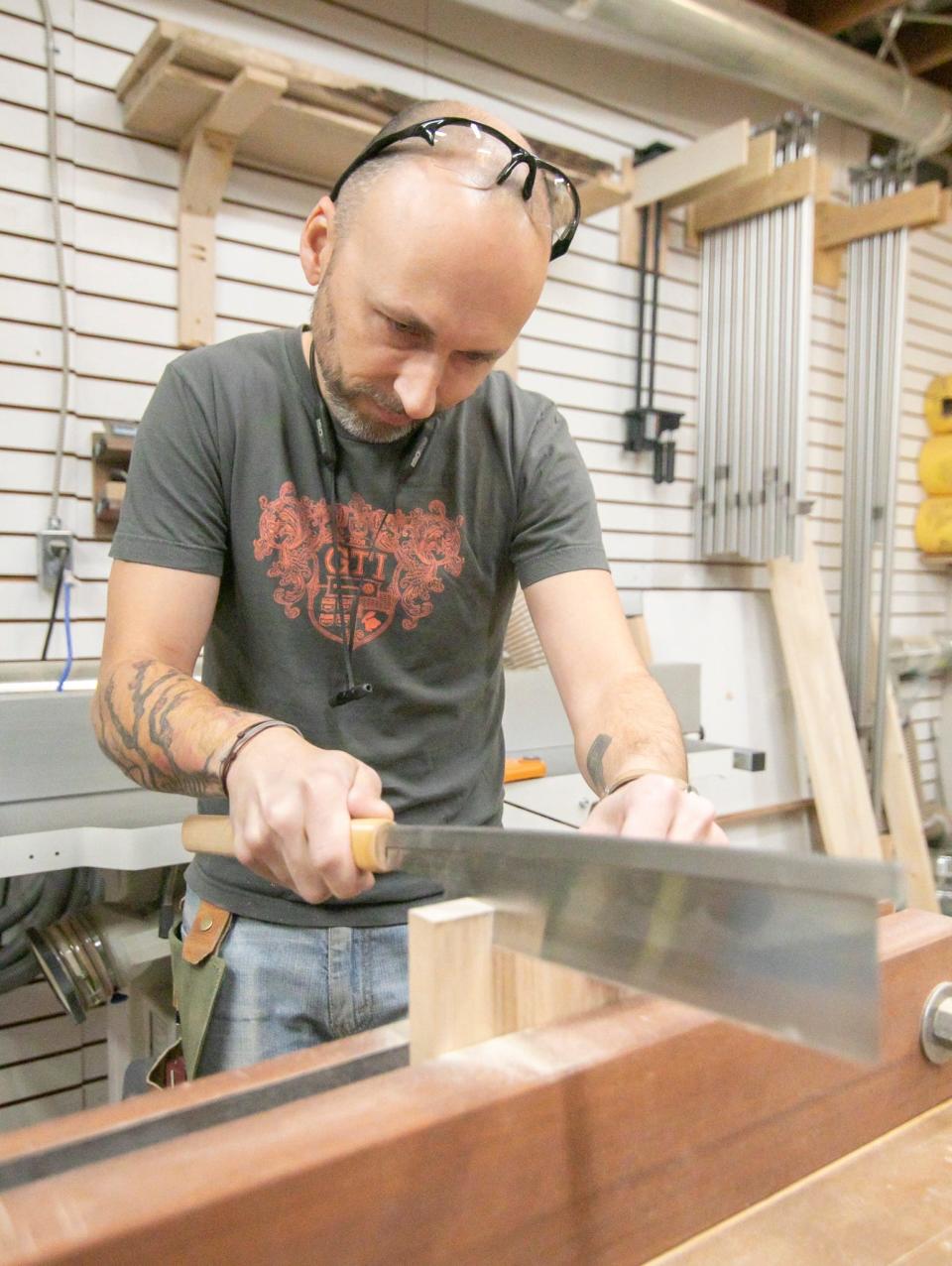 Garrett Roberson cuts a dovetail into a plank of wood to form a drawer on Monday, Nov. 21, 2022.