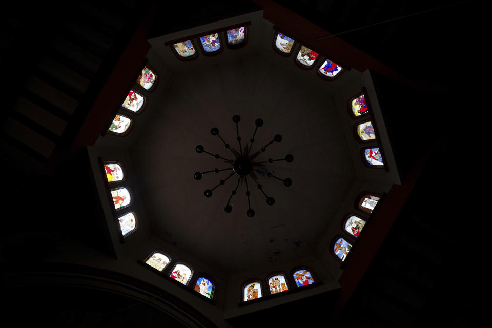 Sunlight illuminates the stained-glass windows of the Espiritu Santo church in the Puerpecha Indigenous community of Comachuen, Wednesday, Jan. 19, 2022. Many things in Comachuen, the church, the bull ring, the charity donations, are paid for by migrants with money they made working in the United States. Many get H2A temporary U.S. work visas; others go without documents. (AP Photo/Fernando Llano)