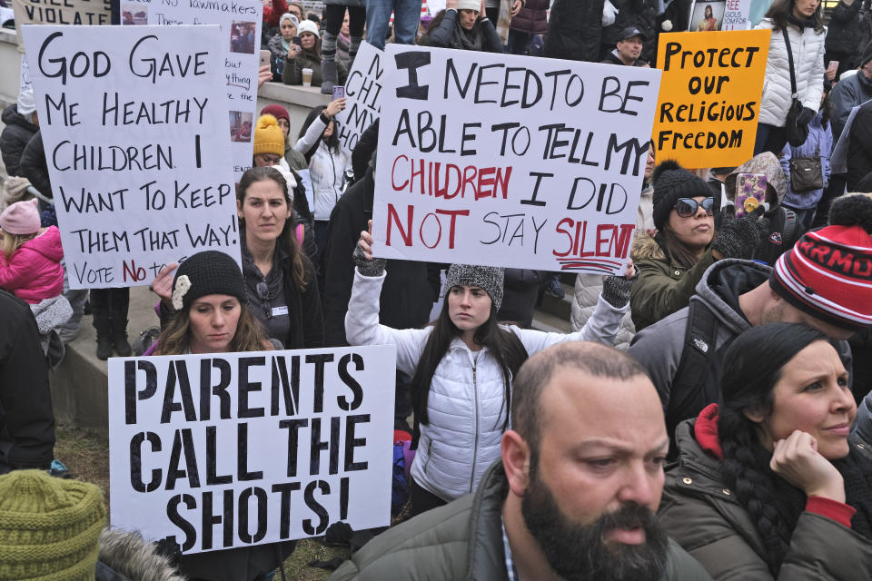 People hold signs during a protest at the state house in Trenton, N.J., Monday, Jan. 13, 2020. New Jersey lawmakers are set to vote Monday on legislation to eliminate most religious exemptions for vaccines for schoolchildren, as opponents crowd the statehouse grounds with flags and banners, including some reading "My Child, My Choice." (AP Photo/Seth Wenig)