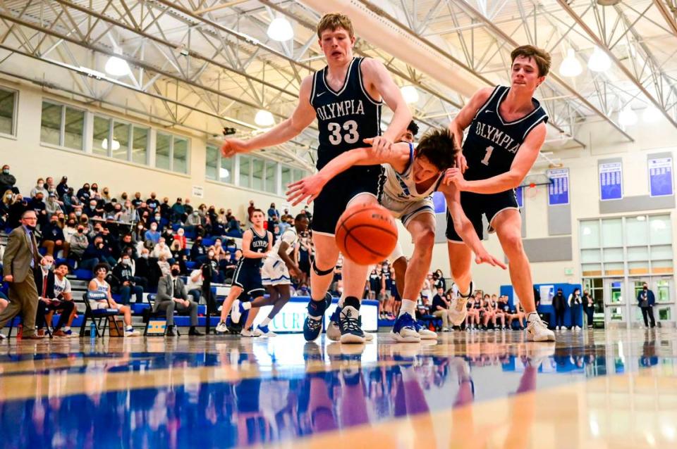 Curtis guard Tyce Paulsen (1) gets sandwiched by Olympia forward Wesley Brewer (33) and guard Caden Roth (1) as they fight for a rebound in the second quarter of a 4A South Puget Sound League game on Friday, Jan. 21, 2022, at Curtis High School in University Place, Wash.