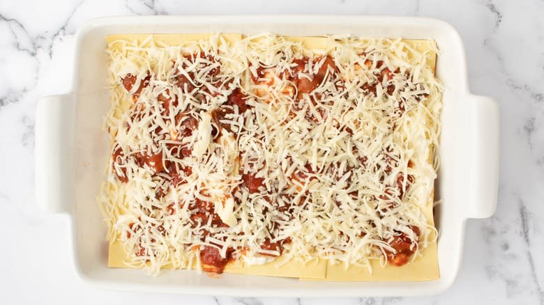 shredded cheese on uncooked lasagna