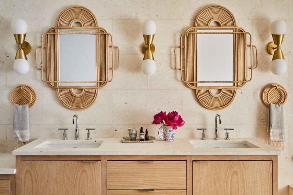 Along with the creation of an entirely new main bedroom came the construction of a fresh primary bath. Rattan mirrors from Ethnicraft and Arteriors sconces steal the show in the simplistic yet chic area of the house.