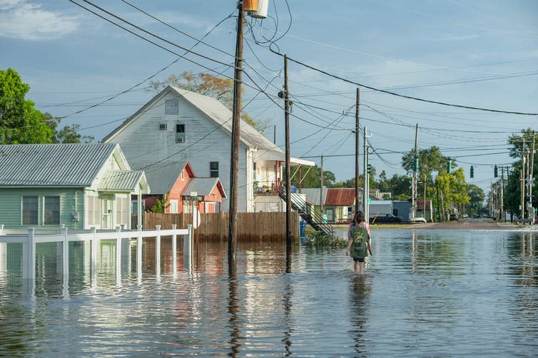 Two people walk through a flooded street.