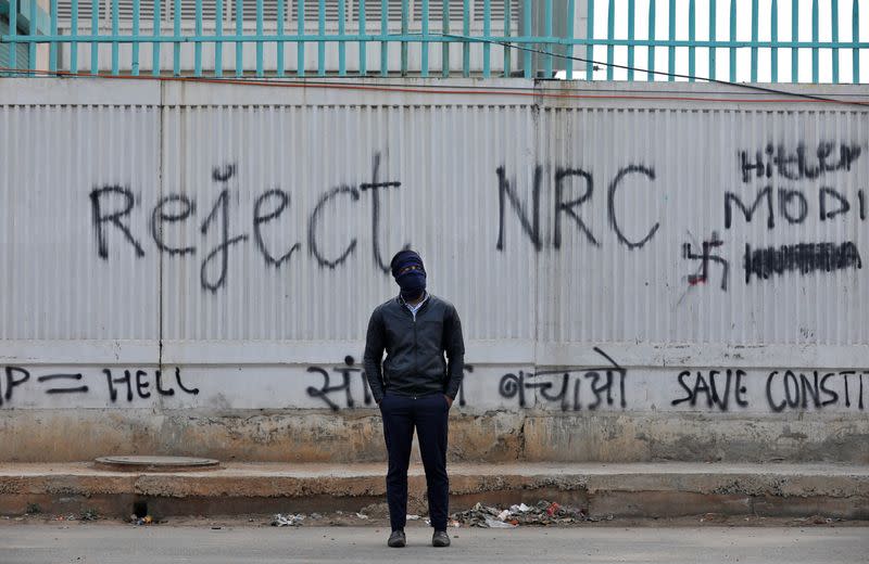 A demonstrator poses in front of a graffiti during a protest against a new citizenship law, in New Delhi