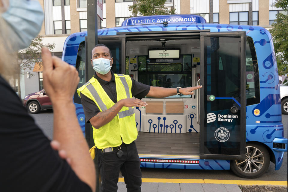 Deployment Manager Jason Peres, center, explains how Relay, an electric autonomous vehicle, works to new riders in Fairfax, Va., Thursday, Oct. 22, 2020. The future of transportation arrived in northern Virginia, looking like a big blue toaster on wheels that can seat six and drive itself through the region’s notorious traffic. State and local officials debuted the Relay system Thursday, an all-electric, autonomous vehicle that will provide free shuttle rides back and forth from the Dunn Loring Metrorail stop to the bustling Mosaic District in Fairfax County, Va.(AP Photo/Jacquelyn Martin)