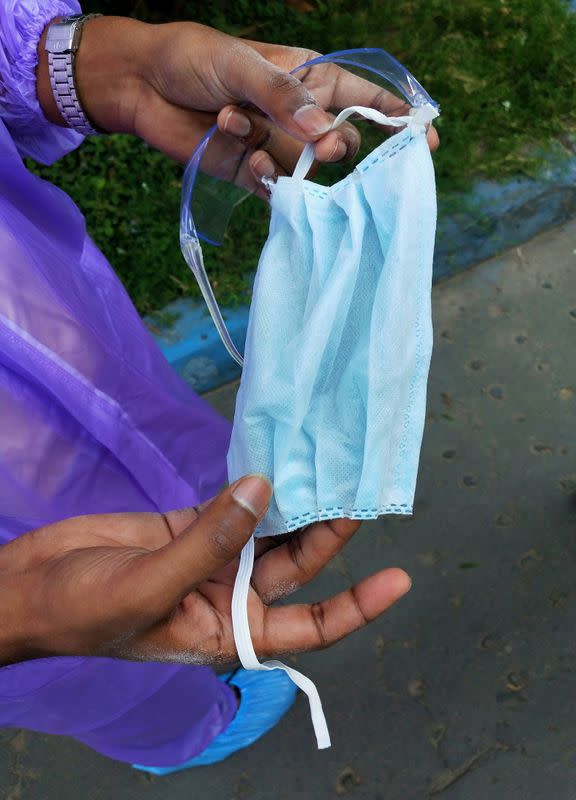 A doctor shows a damaged protective mask at the major coronavirus disease (COVID-19) treatment facility in Kolkata