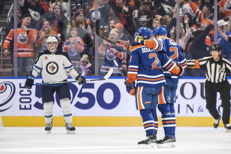 Edmonton Oilers' Evan Bouchard (2) and Leon Draisaitl (29) celebrate a goal as Winnipeg Jets Nate Schmidt (88) looks on during the first period of an NHL hockey game in Edmonton, Alberta, Saturday, Oct. 21, 2023. (Jason Franson/The Canadian Press via AP)
