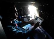 A pilot on board a Vietnamese Air Force aircraft uses a tablet during a search flight over Vietnam's southern sea aimed at finding the Malaysia Airlines' missing flight MH370 on March 14, 2014