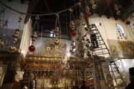 In this Wednesday, Dec. 5, 2018 photo, a worker cleans the dust from a chandelier at the Church of the Nativity, built atop the site where Christians believe Jesus Christ was born, in the West Bank City of Bethlehem. City officials are optimistic that the renovated church will help add to a recent tourism boom and give a boost to the shrinking local Christian population. (AP Photo/Majdi Mohammed)
