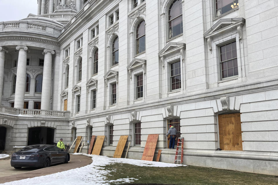 Workers begin boarding up the Wisconsin state Capitol building in Madison on Monday, Jan. 11, 2021. State officials are concerned about the prospects of state-centered violence in the wake of last week's security breaches at the U.S. Capitol. (AP Photo/Todd Richmond)