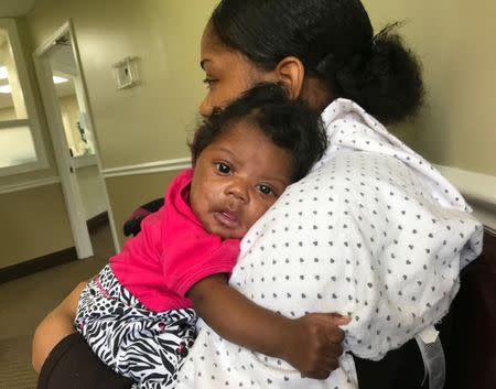 Tiara Rostchild holds her daughter, Ka’mauria J. Thomas during a group session for women to learn from the medical staff and each other about everything from nutrition to postpartum depression in Bay Minette, Alabama, U.S. on June 22, 2017. REUTERS/Jilian Mincer