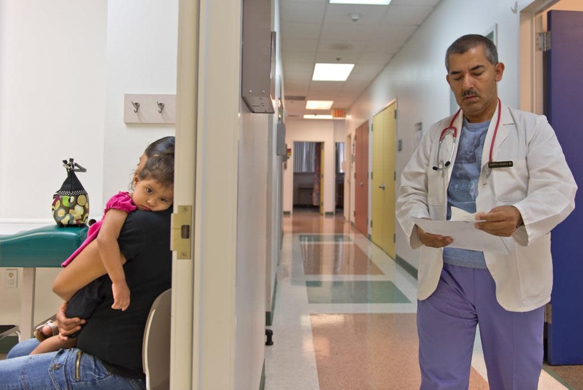 Yesenia Alvarado holds her daughter, Medicaid patient Melanie Almaraz, 2, while waiting to see Dr. Alberto Vasquez for treatment of a fever at Su Clinica Familiar in Harlingen, Texas on Jul. 9, 2013.