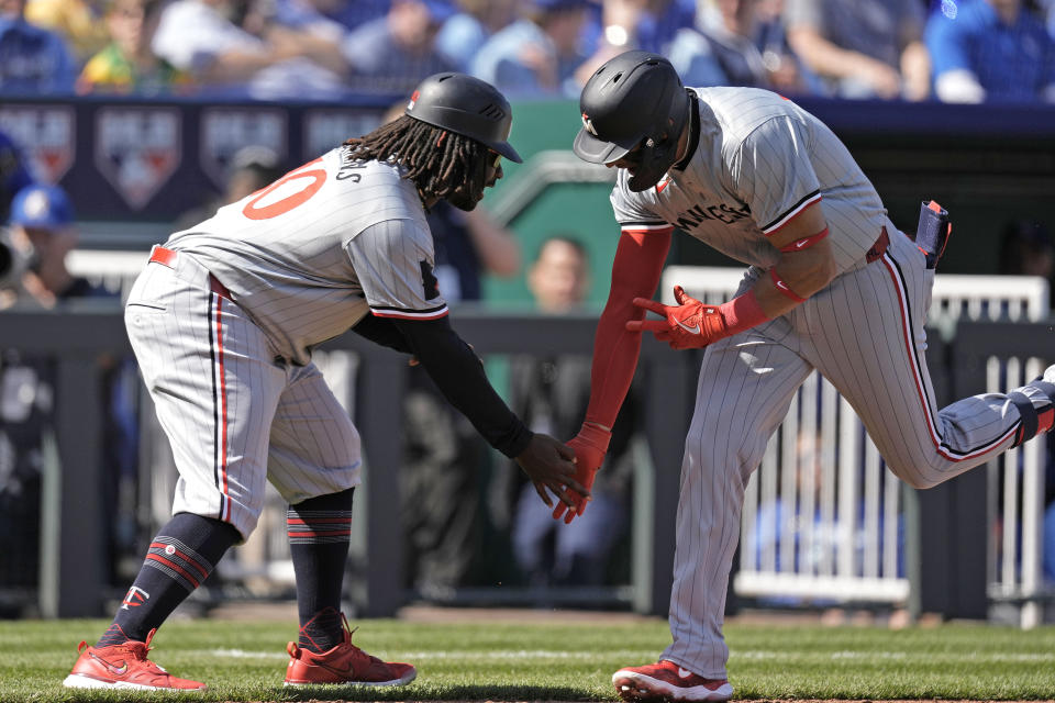 Minnesota Twins' Royce Lewis, right, celebrates with third base coach Tommy Watkins after hitting a solo home run during the first inning of a baseball game against the Kansas City Royals Thursday, March 28, 2024, in Kansas City, Mo. (AP Photo/Charlie Riedel)