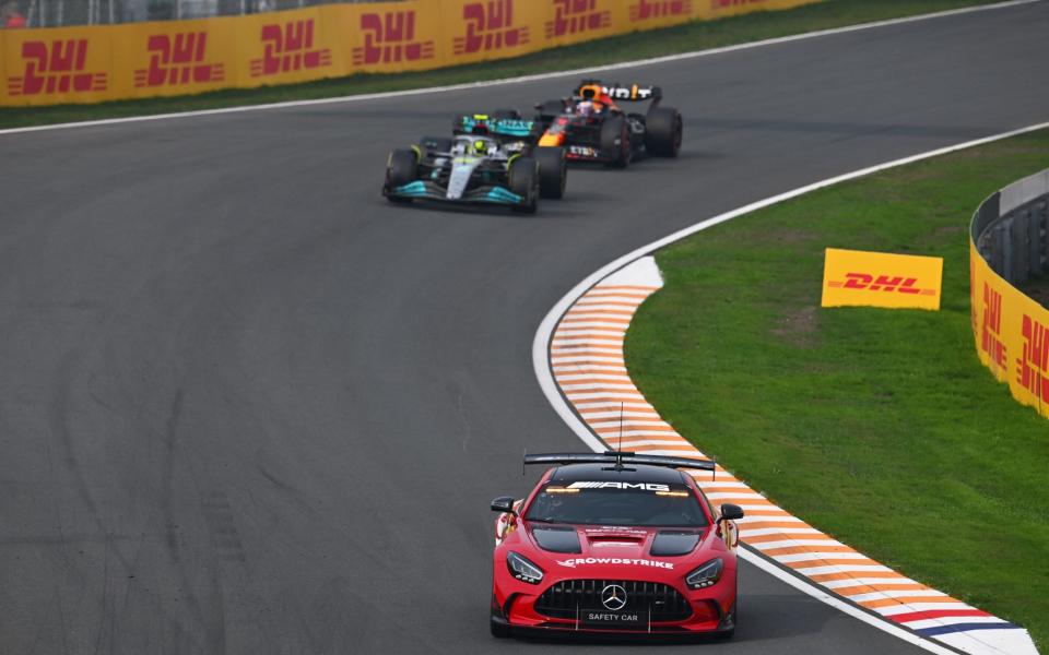 ZANDVOORT, NETHERLANDS - SEPTEMBER 04: The FIA safety car leads Lewis Hamilton of Great Britain driving the (44) Mercedes AMG Petronas F1 Team W13 and Max Verstappen of the Netherlands driving the (1) Oracle Red Bull Racing RB18 during the F1 Grand Prix of The Netherlands at Circuit Zandvoort on September 04, 2022 in Zandvoort, Netherlands. - Clive Mason/Getty Images