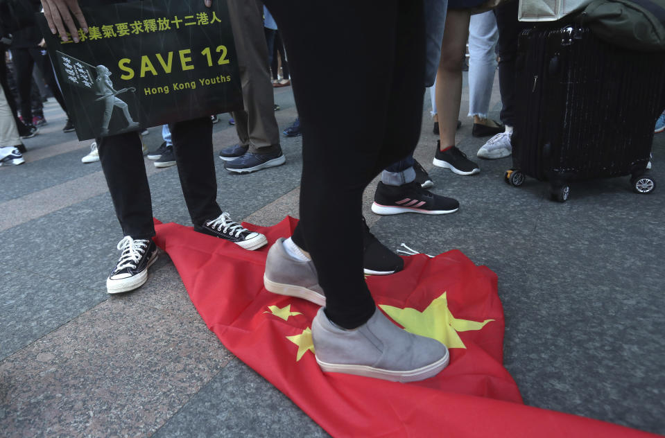 FILE - In this Oct. 25, 2020, file photo, Hong Kong protesters and Taiwanese supporters trample on the Chinese national flag during a march to demand the release the 12 Hong Kong activists detained at sea by Chinese authorities in Taipei, Taiwan. Hong Kong’s government on Friday said it has pulled all of its staff out of Taiwan and accused the island’s government of having “grossly interfered” in the semi-autonomous Chinese city’s internal affairs. (AP Photo/Chiang Ying-ying, File)