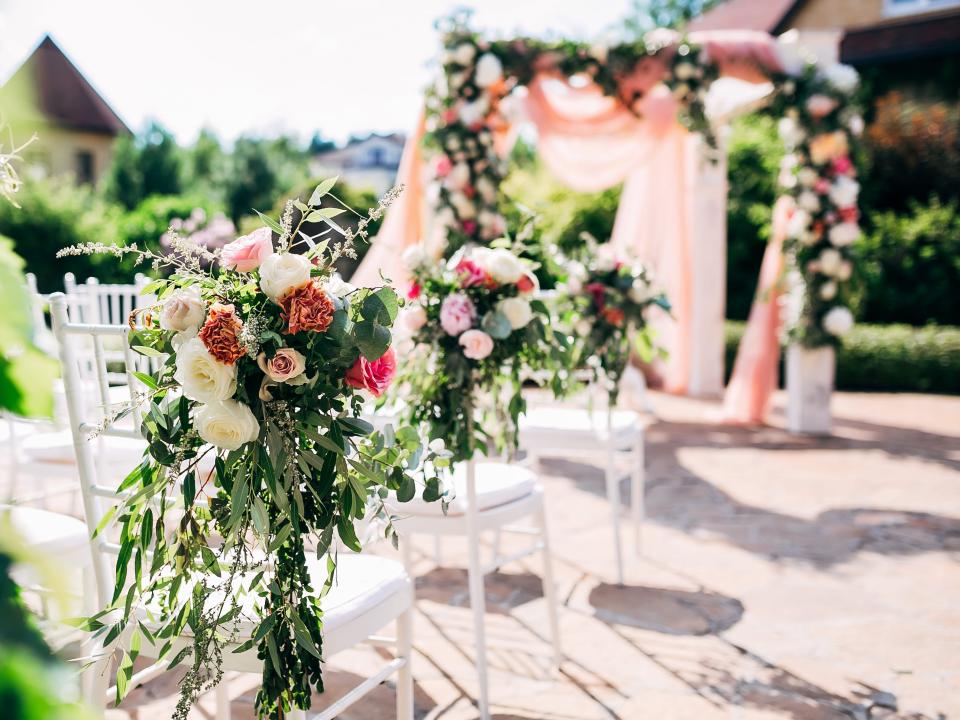 wedding ceremony space set up with white chairs and lots of red and pink flowers