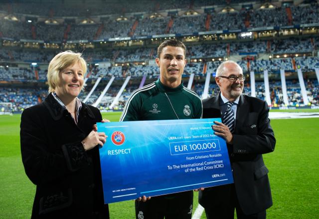 Cristiano Ronaldo (C) of Real Madrid holds a 100,000 Euro UEFA charity cheque standing in between Peter Gillieron (R), member of the UEFA Executive Committee, and Caroline Welch-Ballentine, HR director for the ICRC, prior to the UEFA Champions League Round of 16 first leg match between Real Madrid and Manchester United at Estadio Santiago Bernabeu.