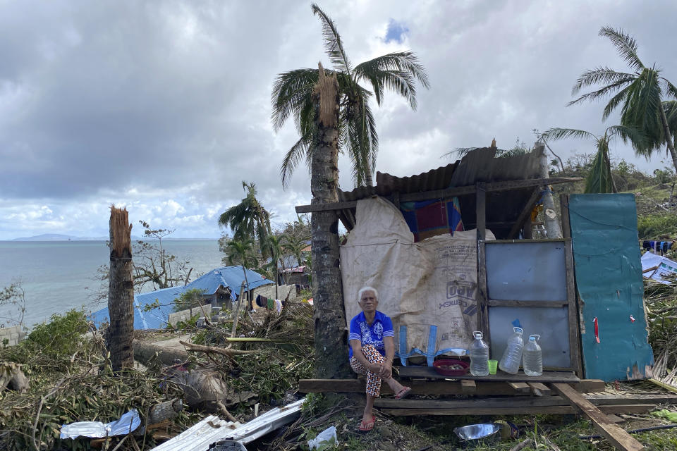 In this photo provided by Greenpeace, a man sits beside damaged homes due to Typhoon Rai in Surigao City, southern Philippines Monday Dec. 20, 2021. The governor of a central Philippine province devastated by Typhoon Rai last week pleaded on radio Tuesday for the government to quickly send food and other aid, warning that without outside help, army troops and police forces would have to be deployed to prevent looting amid growing hunger. (Erwin Mascarinas/Greenpeace via AP)