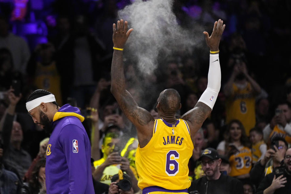 Los Angeles Lakers forward LeBron James, right, tosses powder in the air as forward Anthony Davis walks away prior to an NBA basketball game against the San Antonio Spurs Wednesday, Jan. 25, 2023, in Los Angeles. (AP Photo/Mark J. Terrill)
