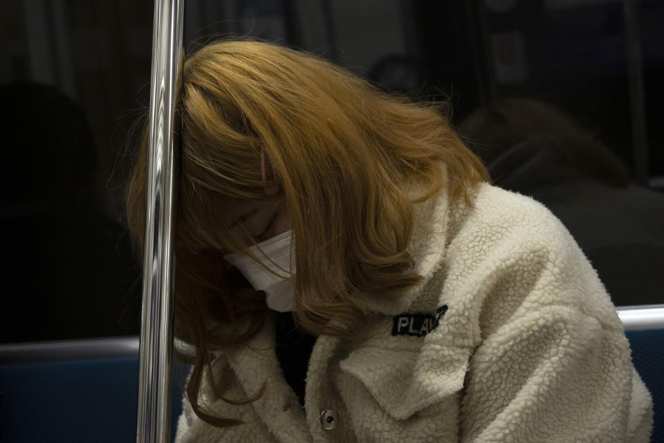 A woman wearing a mask rests her head on a rail while commuting in a train in Tokyo, Monday, March 16, 2020. Asian stock markets and U.S. futures fell Monday after the Federal Reserve slashed its key interest rate to shore up economic growth in the face of mounting global anti-virus controls that are shutting down business and travel. (AP Photo/Jae C. Hong)