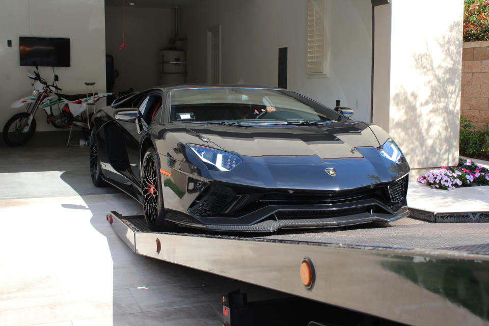 This photo provided by U.S. Immigration and Customs Enforcement shows a special agent with HSI Los Angeles's El Camino Real Financial Crimes Task Force seize a Lamborghini from an Orange County businessman on Thursday, April 6, 2021, in Irvine, Calif. Mustafa Qadiri, 38, of Irvine, was named in a federal grand jury indictment and has pleaded not guilty to charges he obtained $5 million in federal coronavirus-relief loans for phony businesses and then used the money for lavish vacations and to buy a Ferrari, Bentley and Lamborghini, prosecutors said Monday, May 10. (U.S. Immigration and Customs Enforcement via AP)