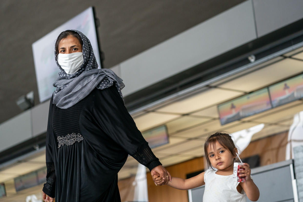 Evacuees who fled Afghanistan walk through the terminal to board buses that will take them to a processing center at Dulles International Airport on Sunday, Aug. 29, 2021. (Kent Nishimura / Los Angeles Times via Getty Images)