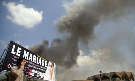 A man speaks in his phone and looks at clouds of smoke at Cairo International Convention Centre (CICC) in Cairo's Nasr City district March 4, 2015. REUTERS/Amr Abdallah Dalsh