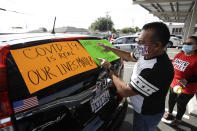 Disney employee Manuel Ortiz decorates his car with signs before a drive-by protest to demand a safe reopening amid the coronavirus pandemic Saturday, June 27, 2020, in Anaheim, Calif. Workers are demanding regular testing, stricter cleaning protocols and higher staffing levels. Disney had originally proposed reopening on July 17th but announced this week it was postponing. (AP Photo/Marcio Jose Sanchez)
