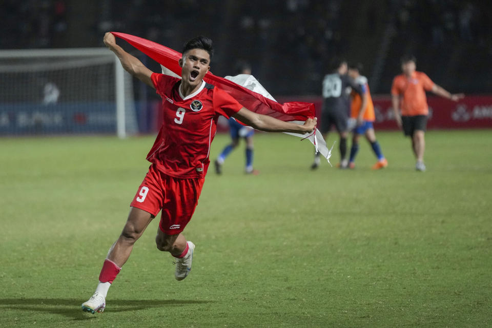 Indonesia's Muhammad Ramadhan celebrates with his country's flag after the winning against Thailand during their men's final soccer match at the 32nd Southeast Asian Games in Phnom Penh, Cambodia, Tuesday, May 16, 2023. (AP Photo/Tatan Syuflana)