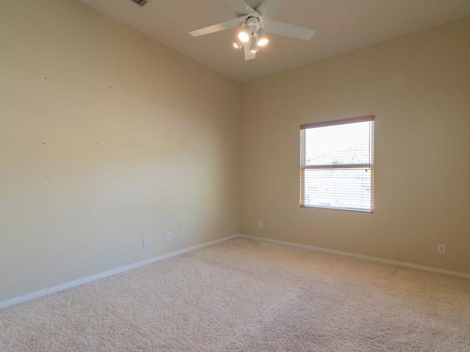 A room with yellow walls and a tan carpet.