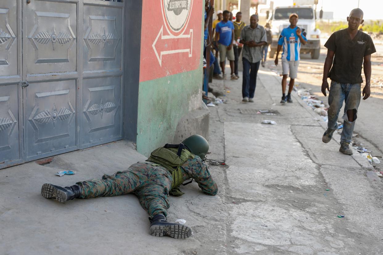 Pedestrians walk past a soldier guarding the area of the international airport in Port-au-Prince, Haiti, on March 4, 2024.
