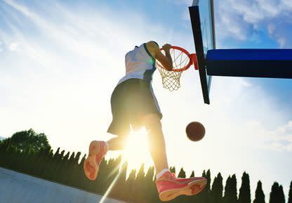 Street basketball player performing power slum dunk.