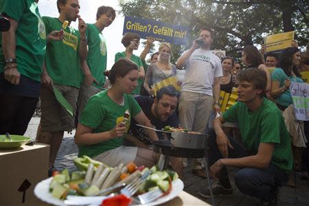 File photo of members of the Green Party, Die Gruenen, dressed in green T-shirts and eating ice cream as they watch a protest of members of the youth wing of the liberal Free Democratic Party (FDP) having a barbecue in front of the Green Party headquarters denouncing a proposed 'Veggie Day' in Berlin August 5, 2013. REUTERS/Thomas Peter/Files