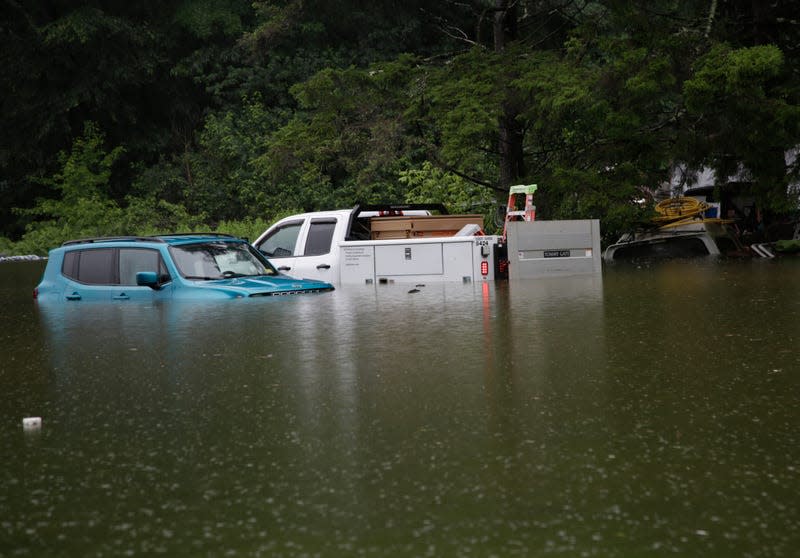 Floodwaters rise in Bridgewater, Vt., on Monday, July 10, 2023, submerging parked vehicles and threatening homes near the Ottauquechee River.