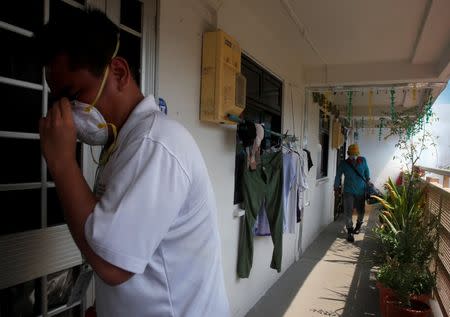 A National Environment Agency officer informs residents as a worker fogs the corridor of a public housing estate in the vicinity where a locally transmitted Zika virus case was discovered in Singapore